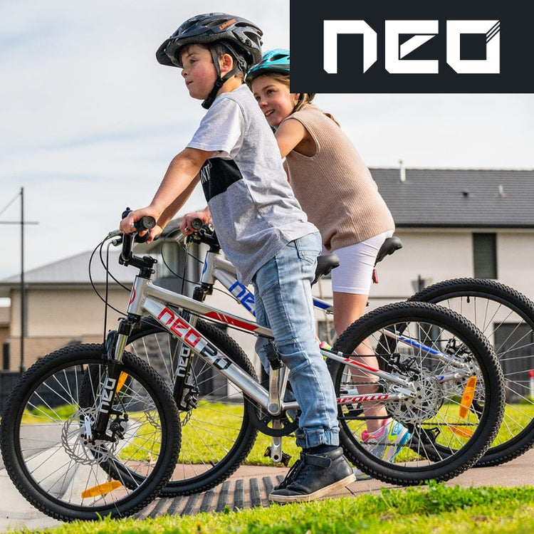 Kids riding Neo bikes with helmets in suburb, The Bicycle Company Mornington Peninsula